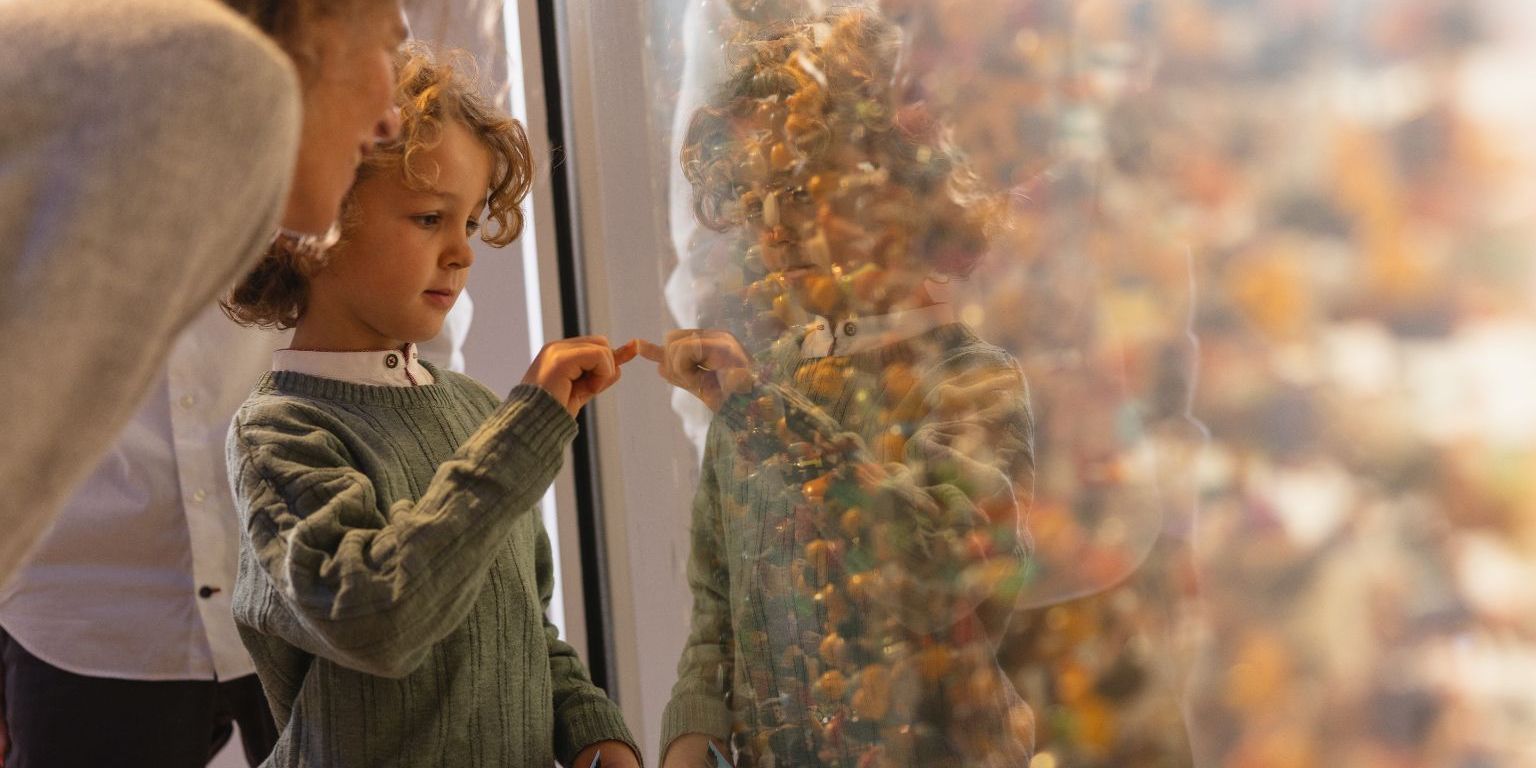 Ein Kind und eine Frau schauen in eine grosse Vitrine mit massenhaft Spielfiguren
